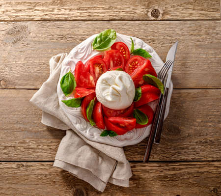 Burrata salad on white vintage plate. Top view of salad with burrata cheese and basil leaves.の写真素材