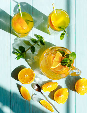 Glasses of lemonade with lemons, oranges and mint leaves on blue wooden background. Top view of lemonade. Summer cold drinks.の写真素材