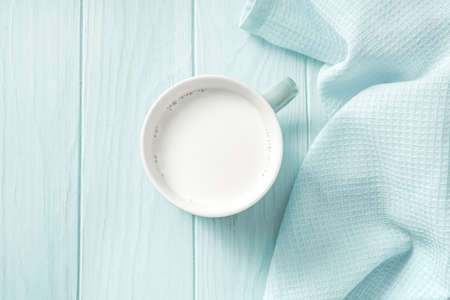 Blue mug of fresh milk on a wooden table. Top view of milk on a blue backgroundの写真素材