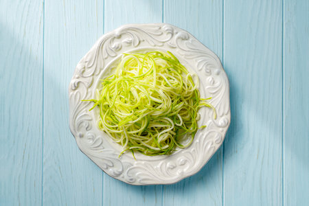 Raw zucchini noodles in vintage white plate. Zucchini and Zucchini spaghetti on blue wooden table...