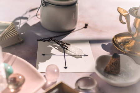 Gemstones for esoteric spiritual practice. Rock crystal pendulum on the table. Divination with a pendulum.の写真素材
