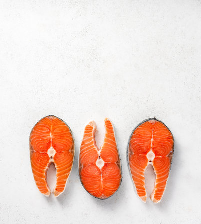 Fresh raw salmon steaks on white concrete table. Top view of fish on white background.の写真素材