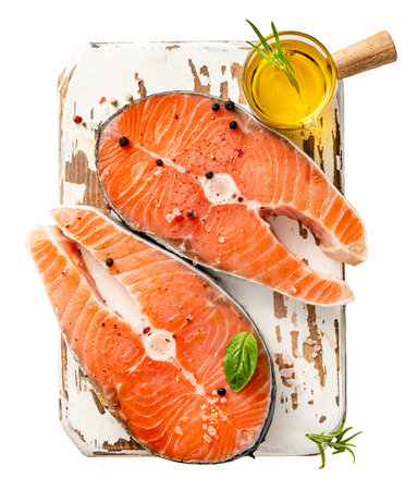 Fresh raw salmon steaks on wooden board with olive oil. Top view of fish on white background.の写真素材