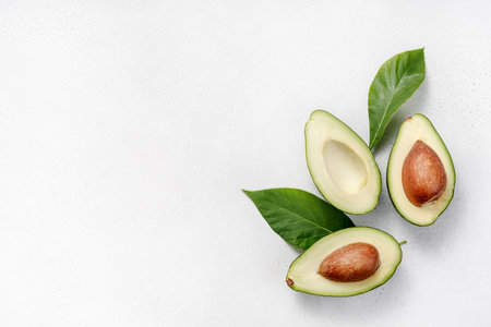 Avocado on white background. Halves of raw avocado fruit with avocado leaves. Top view of avocado.の写真素材