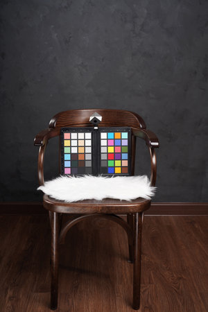 ColorChecker Passport on wooden chair in dark studio. Rainbow color palette for photographerの写真素材