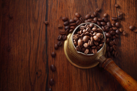 Coffee beans in the turkish dzezva coffee pot on wooden background. Top view.の写真素材