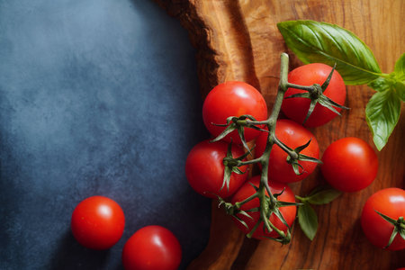 Fresh tomatoes tomatoes on olive blue background. Tomatoes on branch and basil leaves. Background for recipe about tomato sauce. Top view.の写真素材