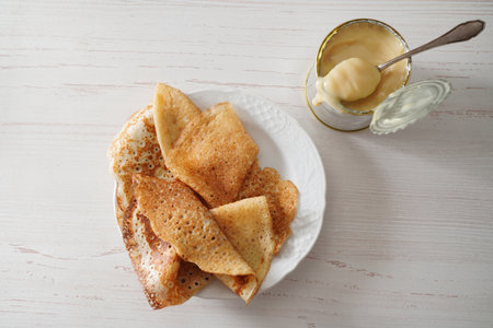 Homemade crepes on white background with condensed milk in tin tan. Top view.の写真素材