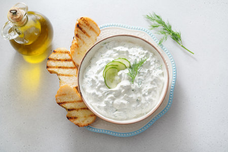 Tzatziki salad with roasted bread in white bowl on white background. Homemade Tzatziki salad with olive oil. Top view.の写真素材