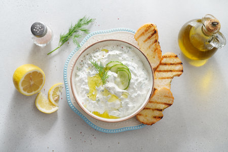 Tzatziki salad with roasted bread in white bowl on white background. Homemade Tzatziki salad with olive oil. Top view.の写真素材