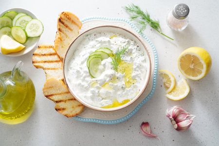 Tzatziki salad with roasted bread in white bowl on white background. Homemade Tzatziki salad with olive oil. Top view.の写真素材