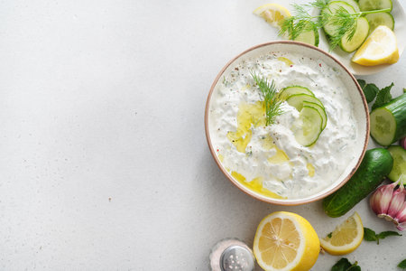 Tzatziki salad with roasted bread in white bowl on white background. Homemade Tzatziki salad with olive oil and copy space. Top view.の写真素材