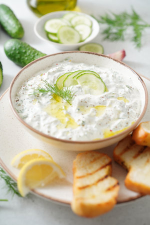 Tzatziki salad with roasted bread in white bowl on white background. Homemade Tzatziki salad with olive oil. Top view.の写真素材