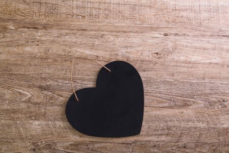Black heart with rope on wood rustic background. Concept for romantic love. Valentines day design. Wooden grunge board.の写真素材