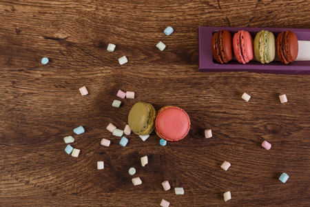 Macaroon cakes with colorful fluffy marshmallows. Almond sweet cookies. Wooden rustic board.の写真素材