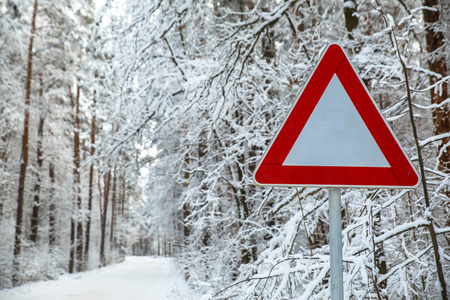 Snowy winter road. Attention sign. Forest with snow-covered trees. Beautiful wintertime.の写真素材