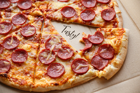 Bitten off a piece pepperoni pizza. Hot homemade food. Sliced fresh italian classic salami pizza. Popular topping with cheese. Baked meal.の写真素材