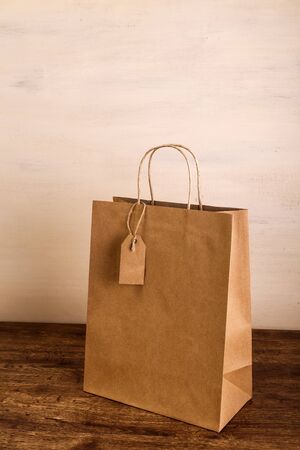 Mockup of blank shopping bag. Brown craft package. Concept for sales or discounts. Recycled paper. Wooden rustic board.の写真素材