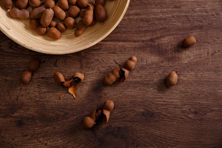 Sweet tamarind on grunge rustic wood background. Natural organic diet food with a lot of vitamins. Plate dish or bowl on wooden board.の写真素材