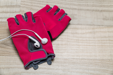 Fitness gym equipment. Workout women gloves. Sport accessories. White headphones for music and mood.の写真素材