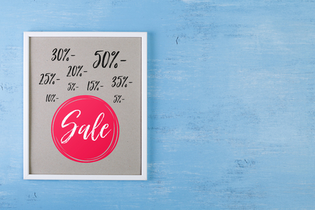 Blank photo frame on blue wood background. Sale discounts design. Painted scraped wooden board....
