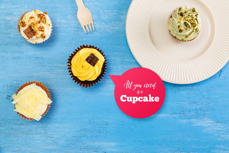 Cupcakes with buttercream. Sweet cake with pistachio cream and small chocolate bar. Dessert with topping. On blue wooden rustic background.の写真素材