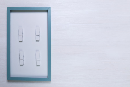 Blank photo frame with wooden pins on white wood background. Painted scraped wooden planks texture or pattern.の写真素材