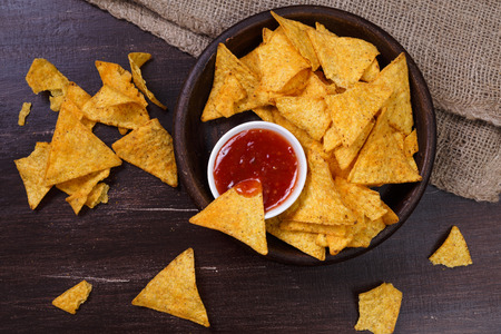 Nachos chips. Delicious salty tortilla with sweet salsa or chilli sauce. Snack on rustic plate....
