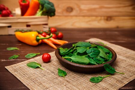 Spinach leaves in bowl. Raw fresh vegetable. Fresh natural plant leaf. Organic bio food on rustic wooden table.の写真素材