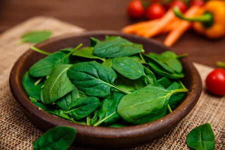 Spinach leaves in bowl. Raw fresh vegetable. Fresh natural plant leaf. Organic bio food on rustic...