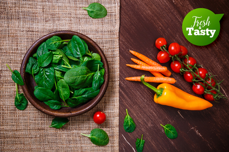 Spinach leaves in bowl. Carrot, pepper and cherry tomatoes. Raw fresh vegetable. Fresh natural plant leaf. Organic bio food on rustic wooden table.の写真素材