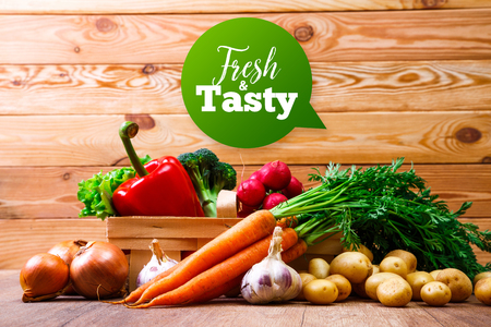 Vegetables. Potatoes, carrot and red pepper. Garlic, onion and brocoli. Lettuce salad and red radish. Wooden basket on planks background.の写真素材