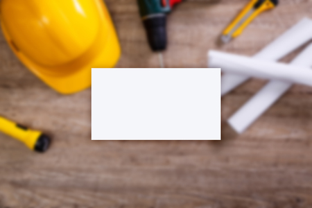 Business card mockup. Yellow helmet, drill and flashlight. Construction concept. Architecture plans and knifes. Worker equipment.の写真素材