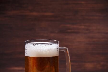 Glass of beer with foam. Mug or pint of ale. Alcohol drink. Pub or bar concept. On rustic wooden...
