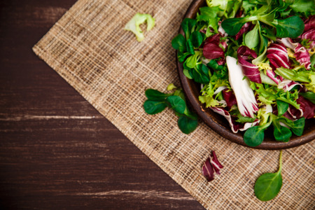 Provence salad. Leaves of endive or chicory, lamb and rose salad. Raw vegetables. On wooden table.の写真素材