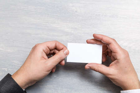 Hand hold blank business card design mockup. Businessman holding visiting card. Business branding template. Person in suit and white shirt.の写真素材