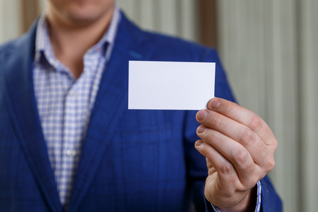 Businessman holding visit card. Man showing blank business card. Person in blue suit. Mock up design.の写真素材