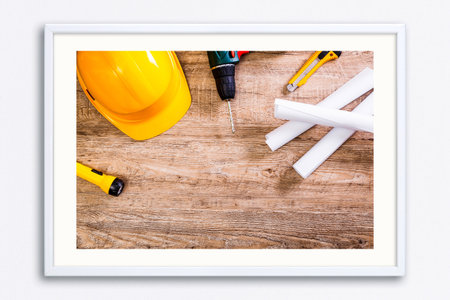 Yellow helmet, drill and flashlight. Construction concept. Architecture plans and knifes. Worker...
