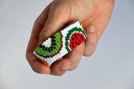 Male hand with woven friendship bracelet handmade of thread with fruit pattern isolated on white backgroundの写真素材