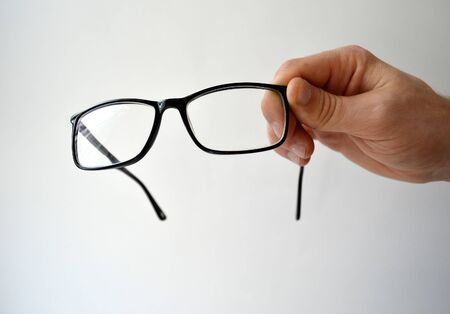Black glasses in man's hand isolated on white backgroundの写真素材