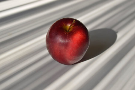 Big red apple on striped dark gray and light gray backgroundの写真素材