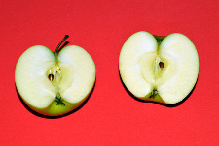 Two halves of a green juicy sliced â€‹â€‹apple on red background