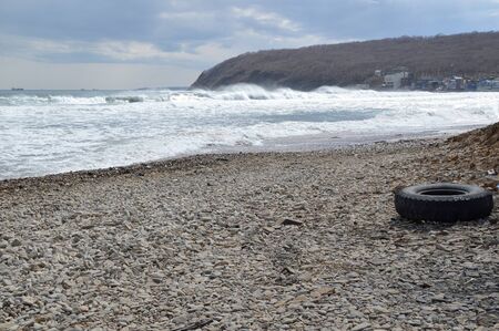 The sea washed ashore car wheel. Environmental pollution concept. copy space. Japanese sea, Russiaの写真素材