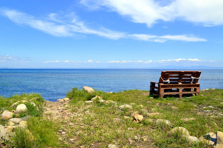 Wooden old bench without people on the background of the Japanese sea on a summer dayの写真素材