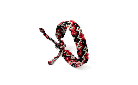 Selective focus of tied woven friendship bracelet with bright colorful pattern handmade of thread...