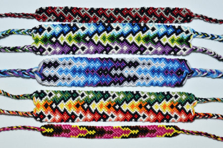Multi-colored woven friendship bracelets handmade of embroidery bright thread with knots on light...
