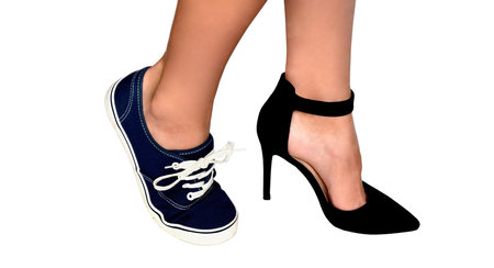 Two different types of shoes: high heels and sneakers on womens feet. Isolated on white background.Concept of females choice of elegance and beauty vs comfort and simplicity.