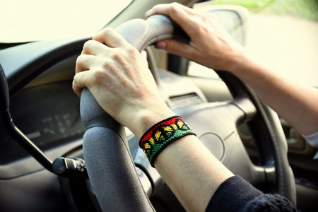 Handmade DIY friendship bracelet with Rasta flag pattern with a peace symbol on womens wrist. Hands...