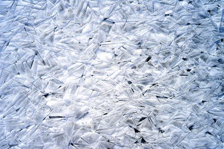 Blurred background made of ice with cracks on a frozen river in winterの写真素材