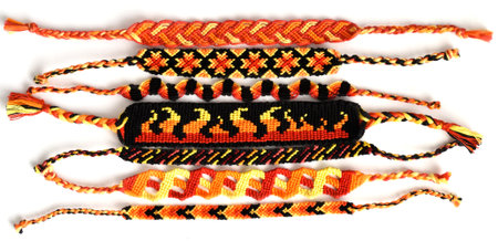 Woven DIY friendship bracelets handmade of embroidery floss with knots in fiery colors